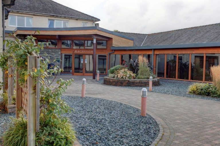 brick pathway curves round gravel plant pit leading up to large glass frontage of the modern Castle Inn Hotel